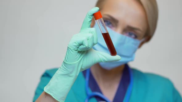 Medical Doctor Nurse Woman Wearing Protective Mask and Latex Gloves - Holding Blood Test Tube