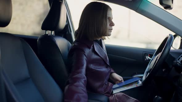 Side View Young Woman Sitting in Car Using Binoculars Looking Away Writing Clues in Sketchbook