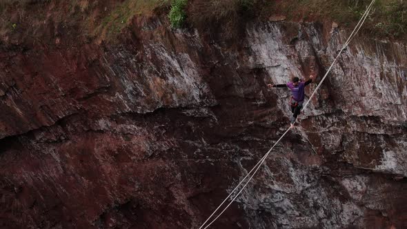 A Man Is Walking on a Tightrope Over a Massive Pit Aerial View