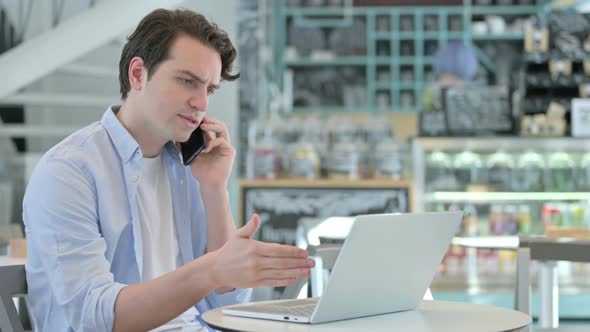 Creative Man with Laptop Talking on Smartphone