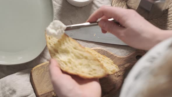 Girl or Woman or Chef Prepares Breakfast and Spreads Soft Cheese or Cream on Crispy Croissant