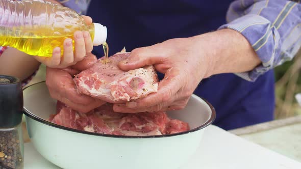 Granddaughter Helps Grandfather Cook Barbecue and Pours Sunflower Oil on Meat