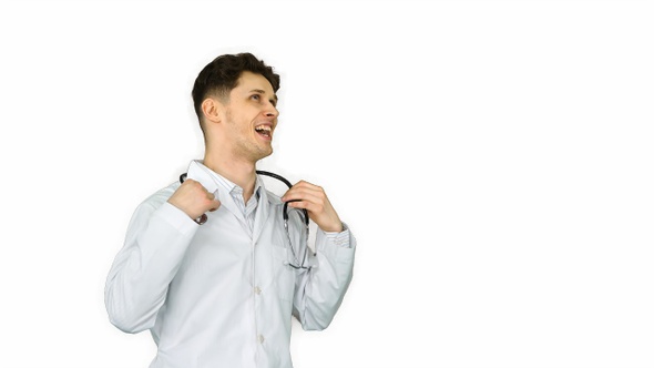 Young doctor wearing lab coat dancing on white background.