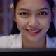 Close-up, Asian woman smiling in front of computer monitor at night. - VideoHive Item for Sale