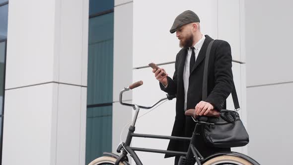 A Handsome Man in a Suit Looks at the Phone Near the Business Center