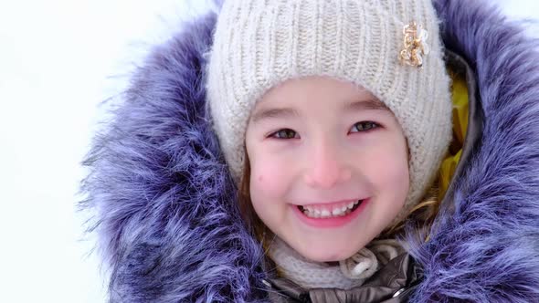 Portrait of a cheerful and happy 5-year-old girl in close-up in winter warm clothes