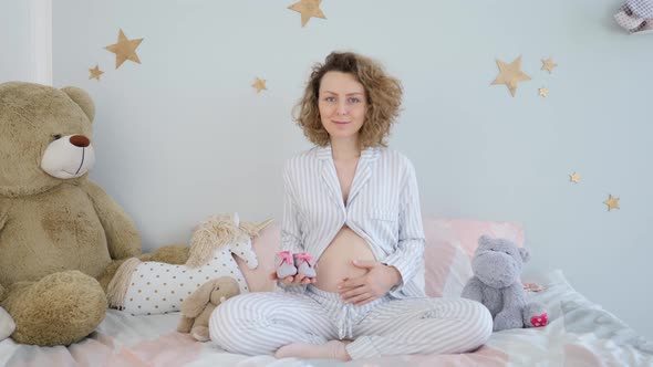 Happy Pregnant Woman Expecting Her Baby Sitting In Nursery Room