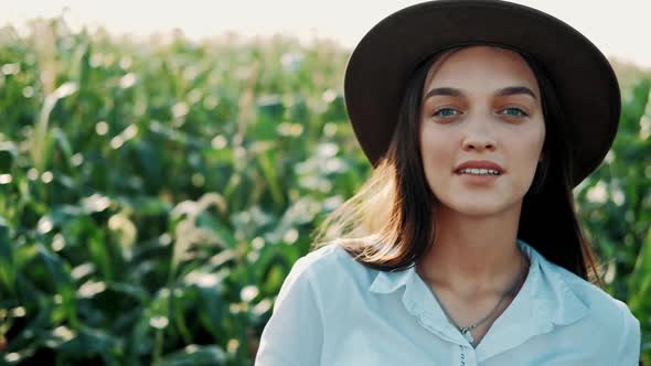 Close-up Portrait of Beautiful Young Girl in Hat Standing at a Corn Field Smiling and Looking