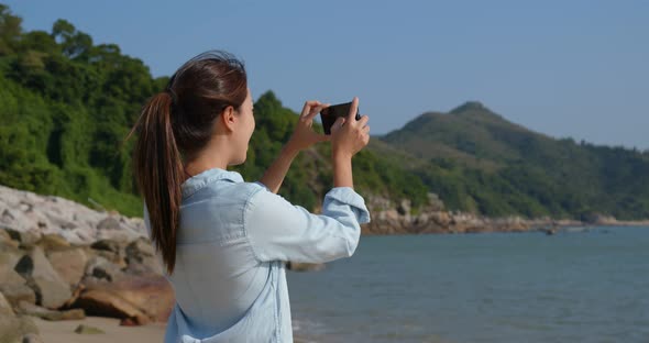 Woman take photo on cellphone at seaside