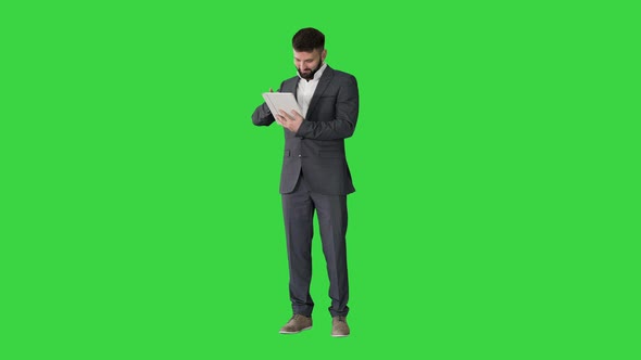 Businessman Standing and Using Tablet Computer on a Green Screen, Chroma Key