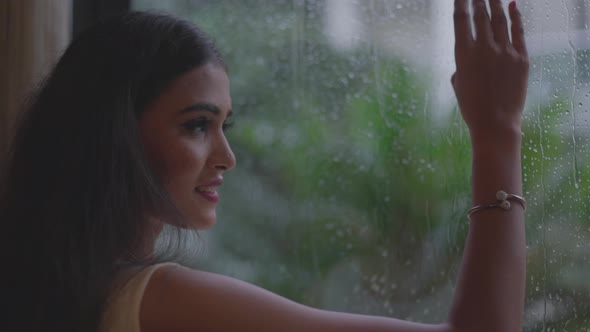 Close up shot of smiling face enjoying the rainy weather while seeing outside the window at Diu city