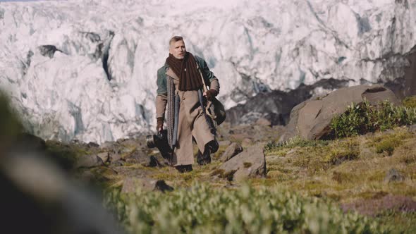 Traveller Carrying Guitar Case On Rocky Hill Next To Glacier