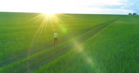 Sporty Child Runs Through a Green Wheat Field. Evening Sport Training Exercises at Rural Meadow. A