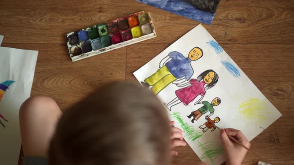 A Child Paints a Drawing on the Floor with Watercolors