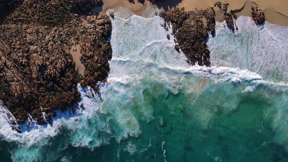 Topdown of beautiful waves breaking over patterned rocks at Injidup beach Western Australia