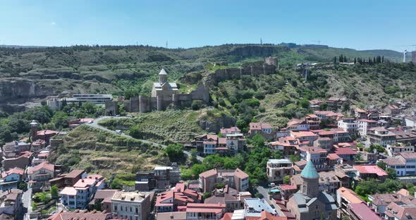 Aerial view of Tbilisi old town buildings and Narikala fortress landmark on hill