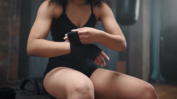 Muscled Woman in Black Outfit Wraps Hand with Boxing Bandage