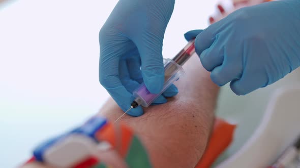 Medical worker in gloves taking blood sample from vein.