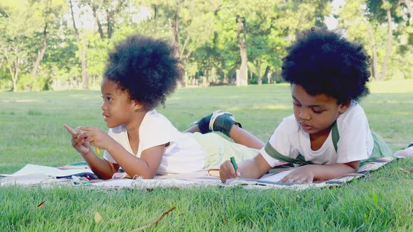 Outdoor portrait of a cute black boy and girl lying on the grass 