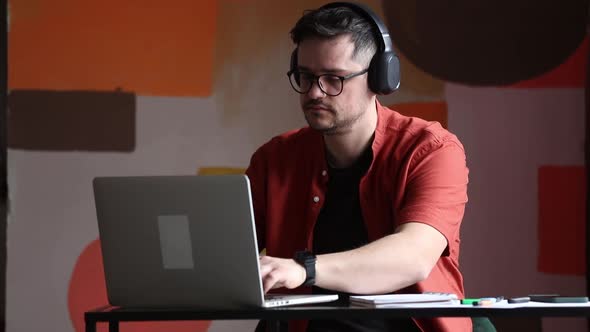 Man working in home office at table with laptop computer and notebook