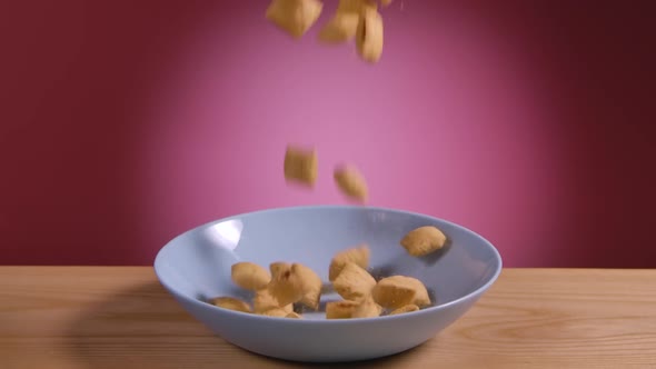 Appetizing Crunchy Corn Pads Fall Into a White Plate on a Pink Background