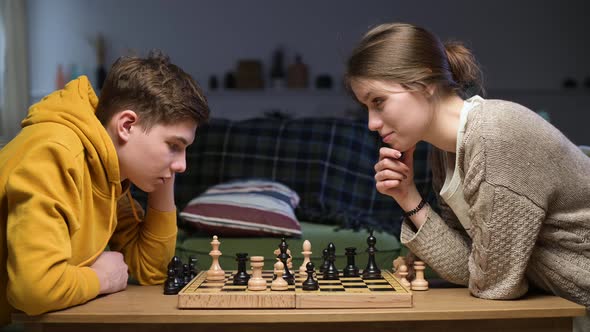 Young people are pensively looking at the chessboard, reflecting on the moves