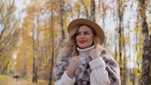 Portrait of a Smiling Happy Cheerful Woman in a Brown Hat in Autumn Park