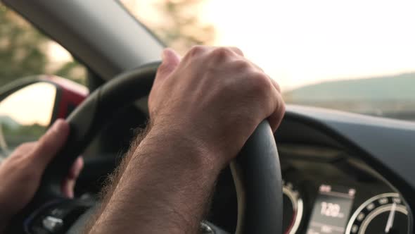 Driver Holds Steering Wheel of Car Driving in Highland