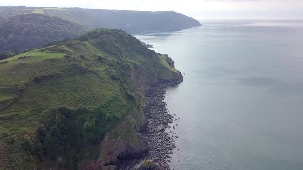 Aerial tracking forward diagonally looking west along the Exmoor coast at the valley of rocks. Wring
