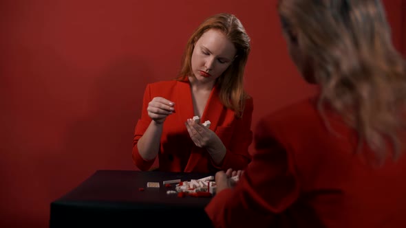 Beautiful young girls sit at a table opposite each other and collect the constructor