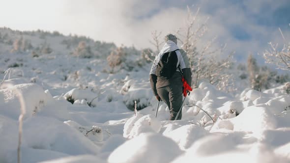 A Young Woman is Slowly Climbing to the Top of a Snowcapped Mountain