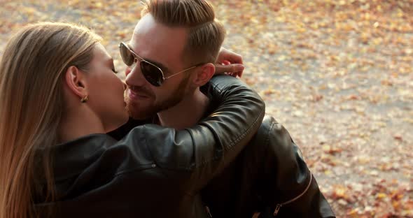 A Brutal Man with Sunglasses Kisses with His Beloved in Embraces Outdoors