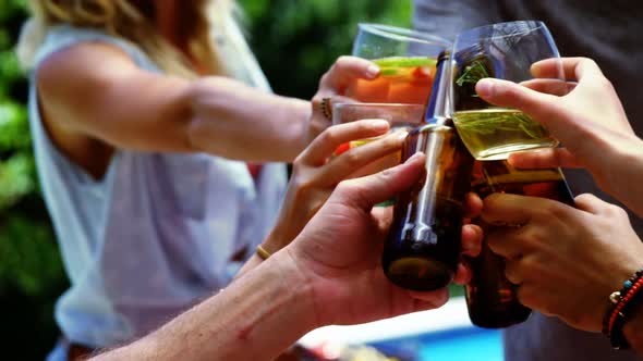 Group of happy friends toasting glasses of drinks at outdoors barbecue party