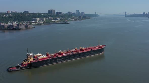 A drone view of a large red barge on the Hudson River in NY on a sunny day. The camera truck right a