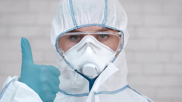 Medical Worker Gesturing ThumbsUp Wearing Protective Hazmat Suit White Background