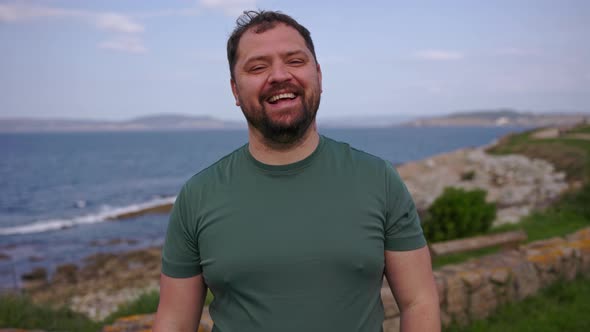 A Man Laughs and Touches His Beard in Nature