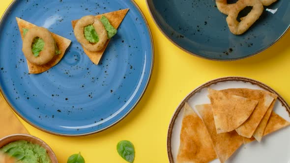 Vertical Flat Lay Video Man Takes Nachos with Pesto and Onion Rings From the Plate