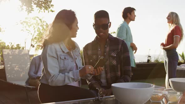 Two friends drinking discussing and using a smartphone on a rooftop