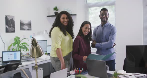 Portrait of smiling diverse group of business people looking at camera in modern office