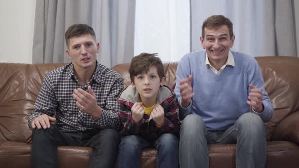 Portrait of Caucasian Multi-generation Family of Football Fans Watching Match on TV. Middle Aged Man