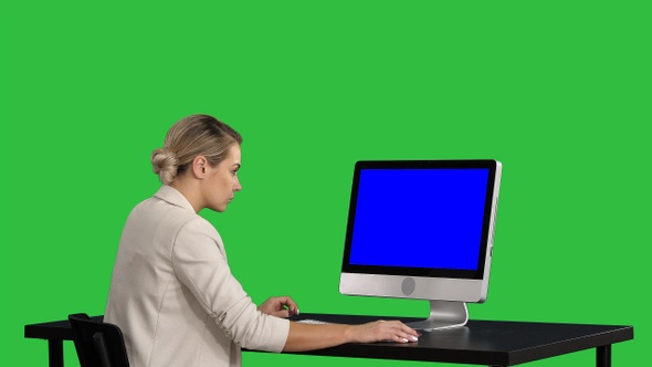 Business person works at table with computer on a Green