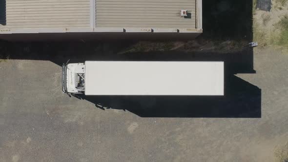 Smooth aerial ascent above truck about to leave depot.