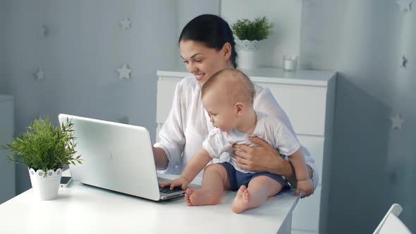 Young Mother Working with Laptop at Home