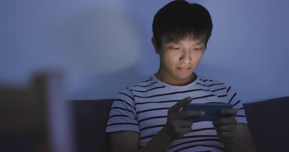 Man playing mobile game on cellphone at night