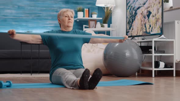 Senior Person Pulling Resistance Band to Exercise on Yoga Mat