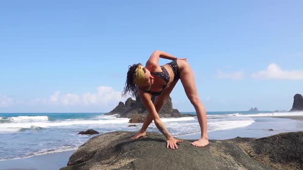 Woman Doing Gymnastics on the Ocean Near the Water Against the Waves. Yoga Practice. Healthy
