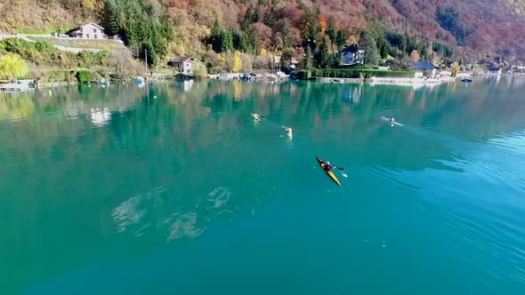 Three kayakers paddle in a scenic mountain lake.