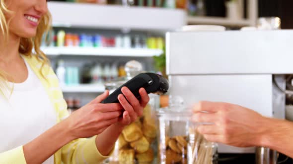 Customer making payment through payment terminal machine at counter