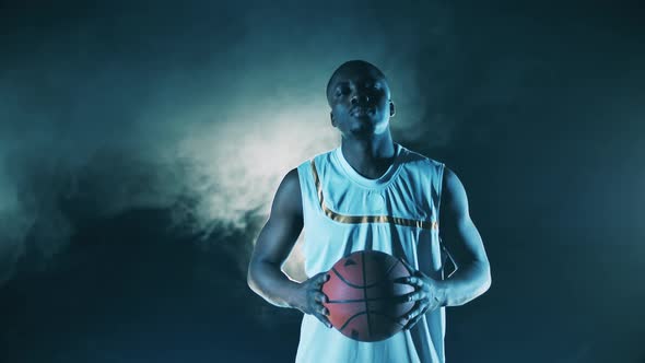 Male Player with a Basketball is Looking Into the Camera