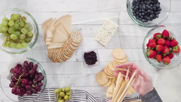 Time lapse. Flat lay. Step by step. Arranging cheese platter with fresh fruits, gourmet cheese, and 
